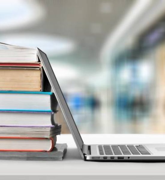 Stack of books with laptop on wooden table